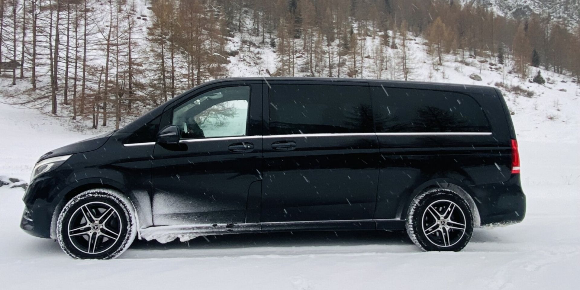 Black van parked on a snowy landscape with trees in the background