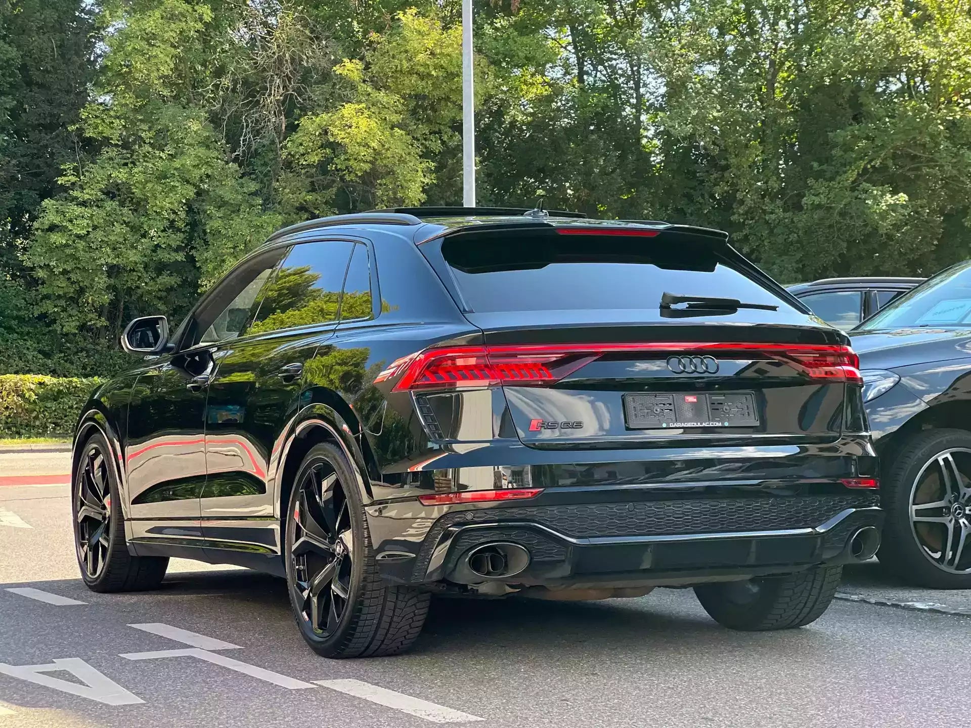 Black Audi SUV parked on a road with trees in the background