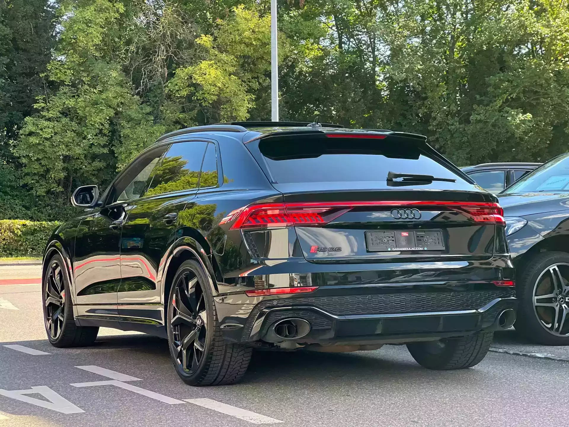 Black Audi SUV parked on a road with trees in the background