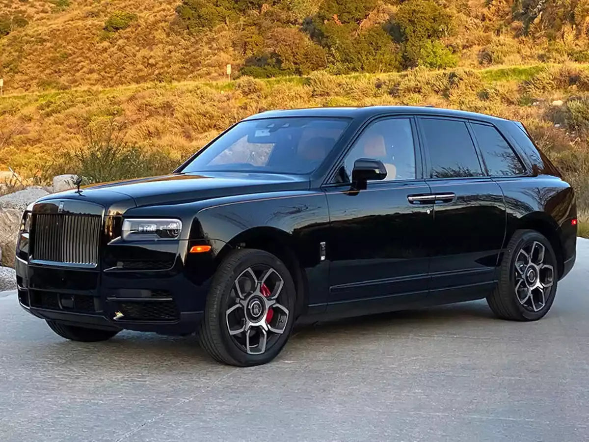 Black luxury SUV parked on a paved road with a scenic background