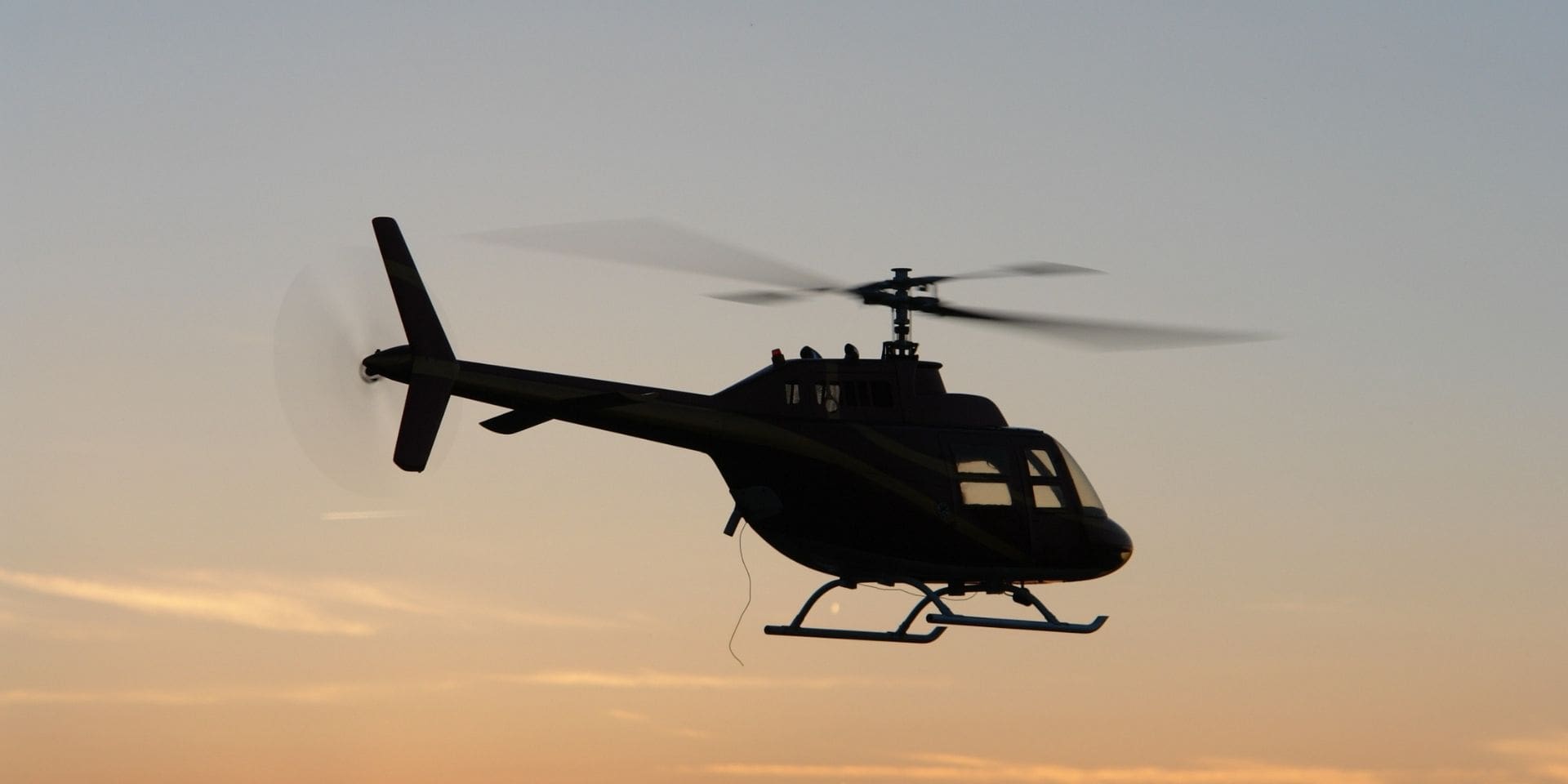 Silhouette of a helicopter against a sunset sky
