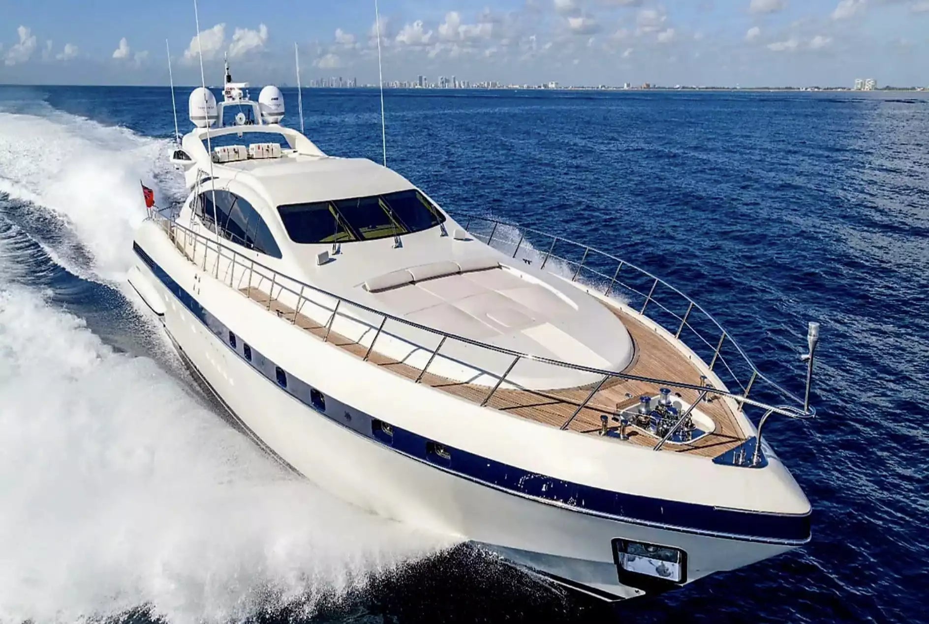 Luxury yacht speeding across the ocean with a clear sky.