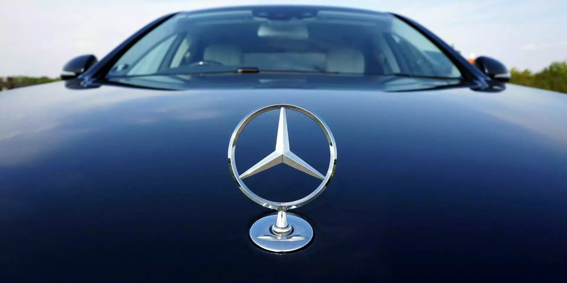 Mercedes-Benz logo on a car hood with a blurred background