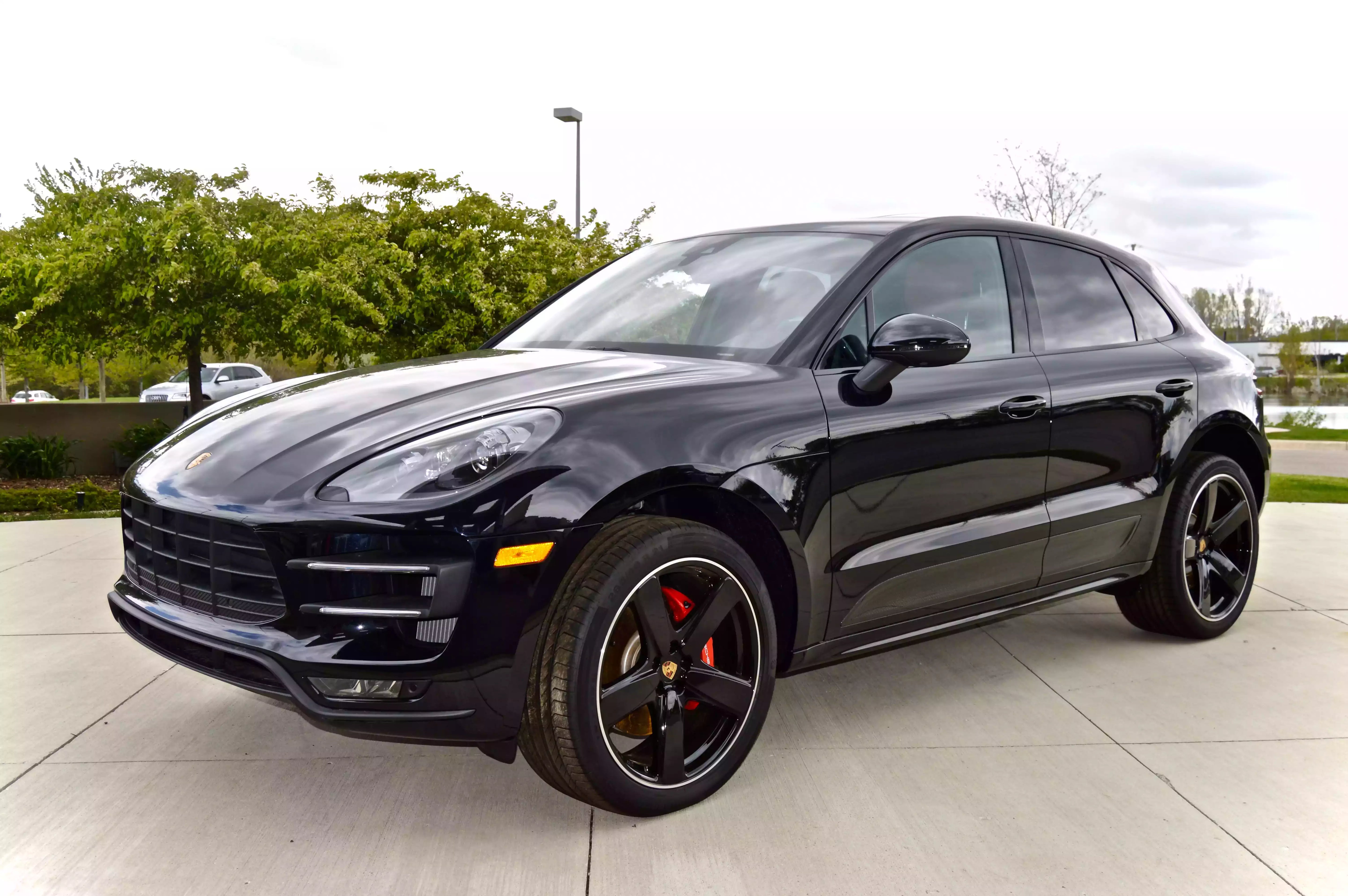 Black Porsche SUV parked on a concrete surface with greenery in the background