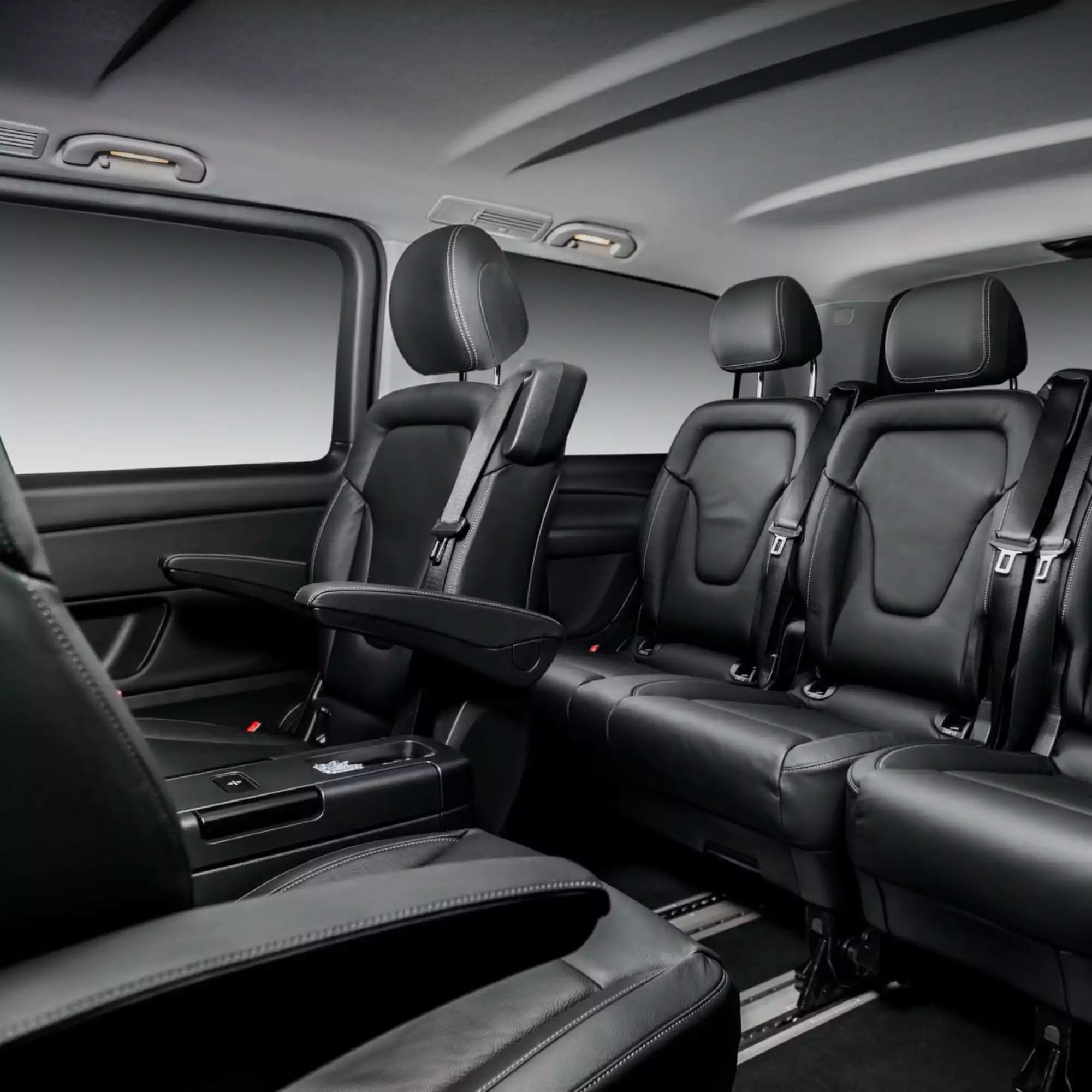 Black leather interior of a vehicle with multiple seats.