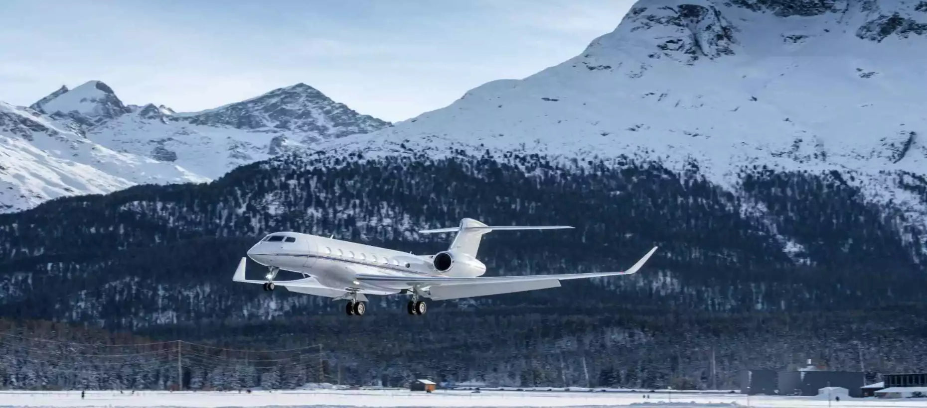 Private jet taking off from a snowy runway with mountains in the background