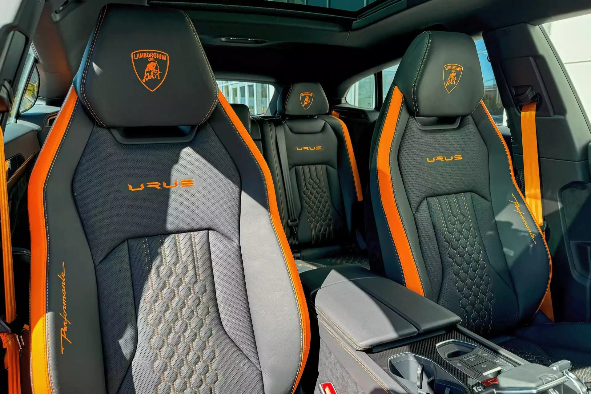 Luxury car interior with gray and orange seats featuring the Urus logo.