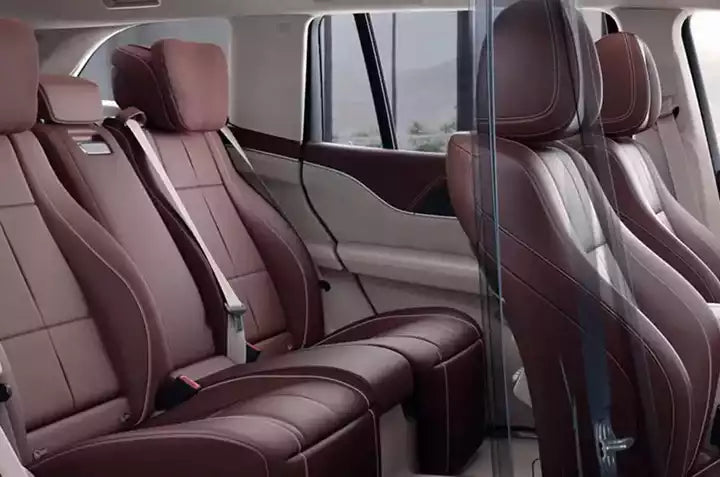 Luxury vehicle interior with brown leather seats and a clear plastic partition.