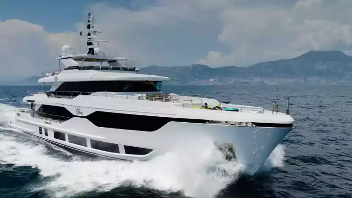 Large white yacht on the water with mountains in the background