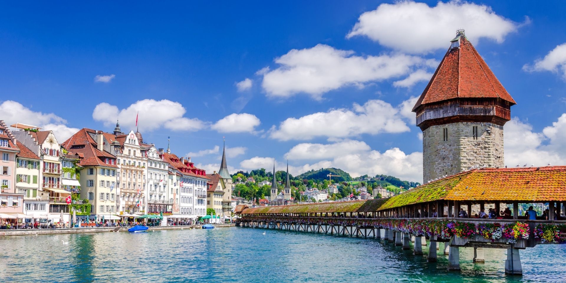 Town with a famous bridge and clock tower under a blue sky with clouds.