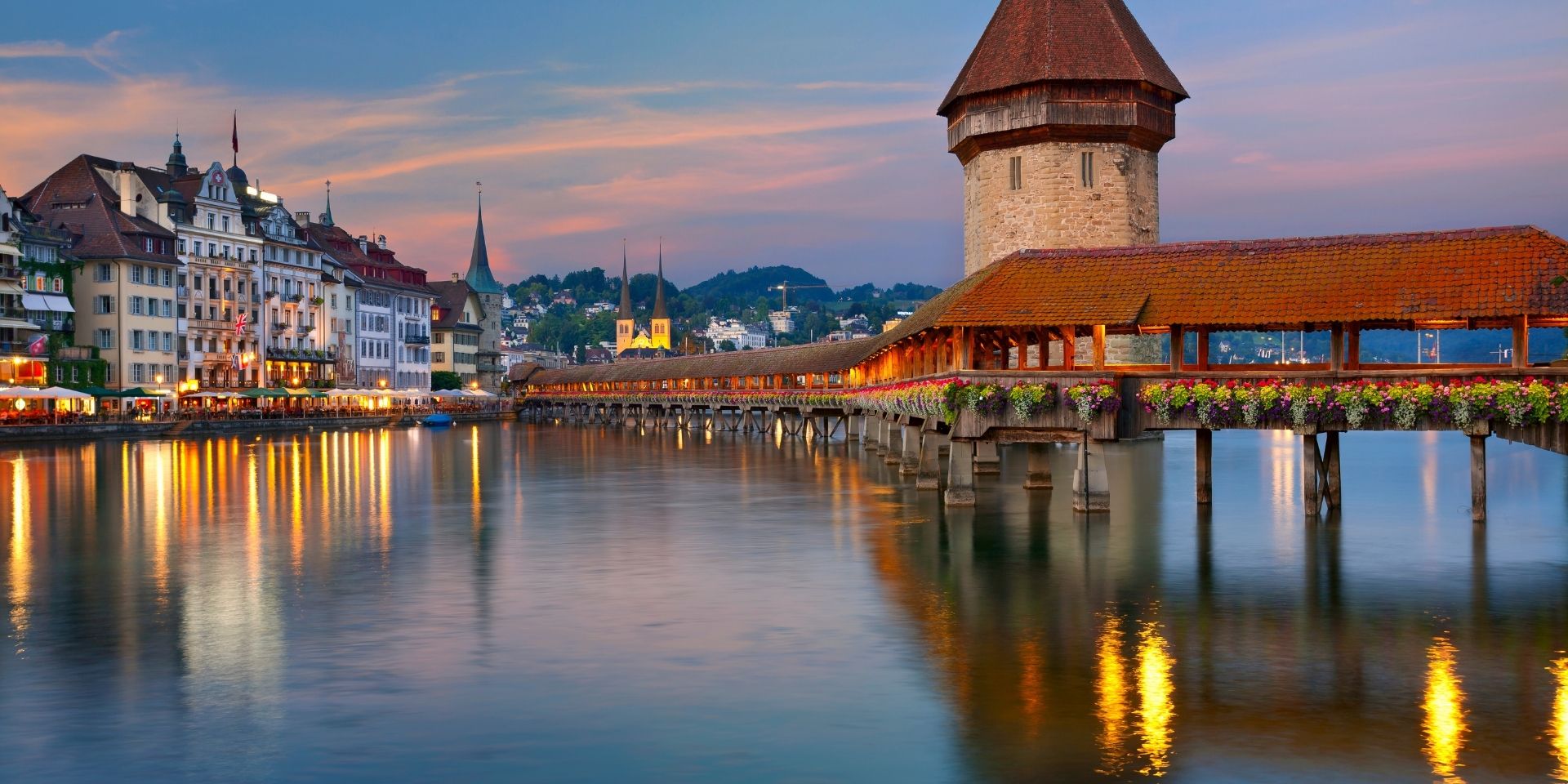 Evening view of a historic town with a covered bridge over a river, Switzerland.