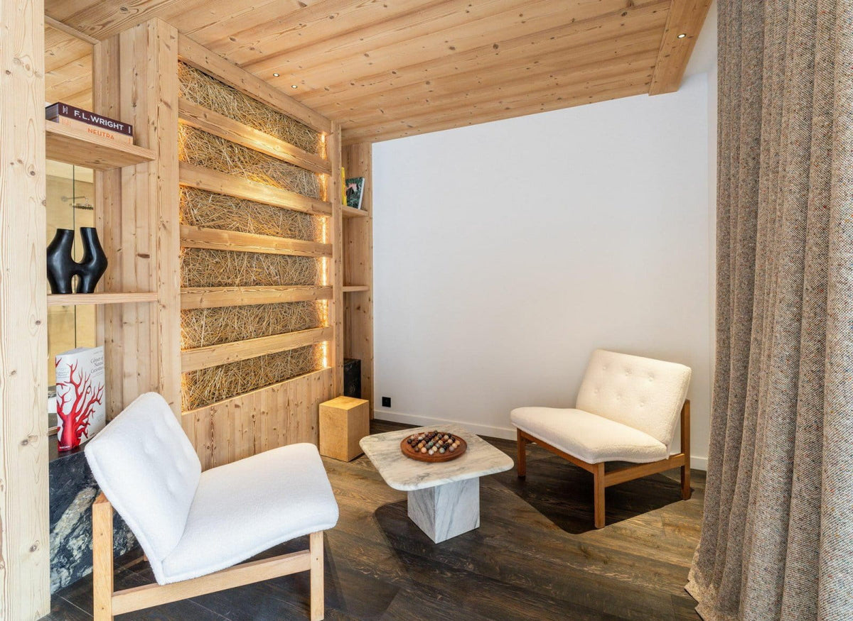 A modern interior room with two upholstered lounge chairs, a small marble-top coffee table, exposed wood shelving, and a textured curtain, suggesting a furniture or home decor listing.