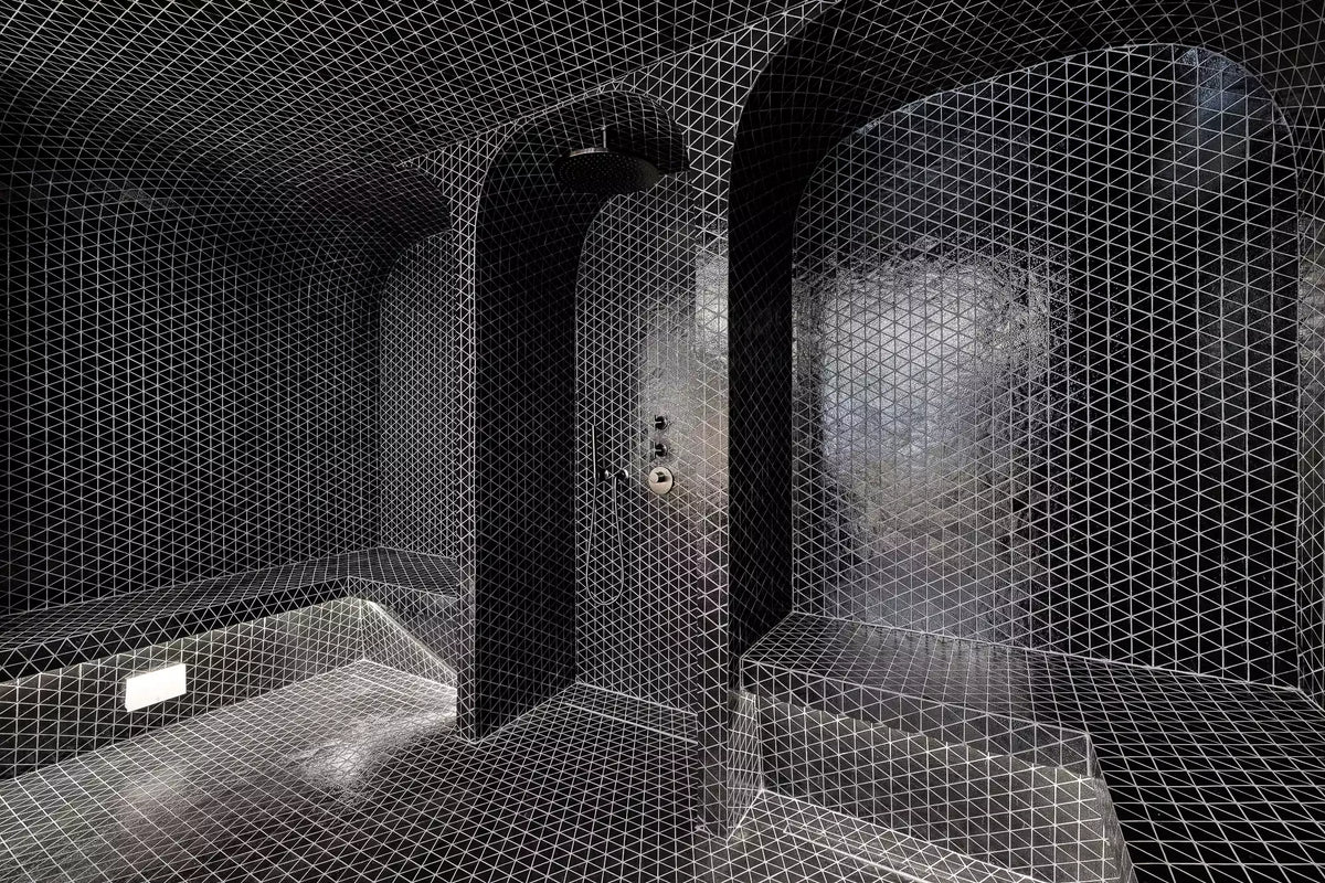 A dark, modern bathroom or shower room with arched alcoves, textured walls, and a prominent white geometric wire-grid overlay across the entire scene.