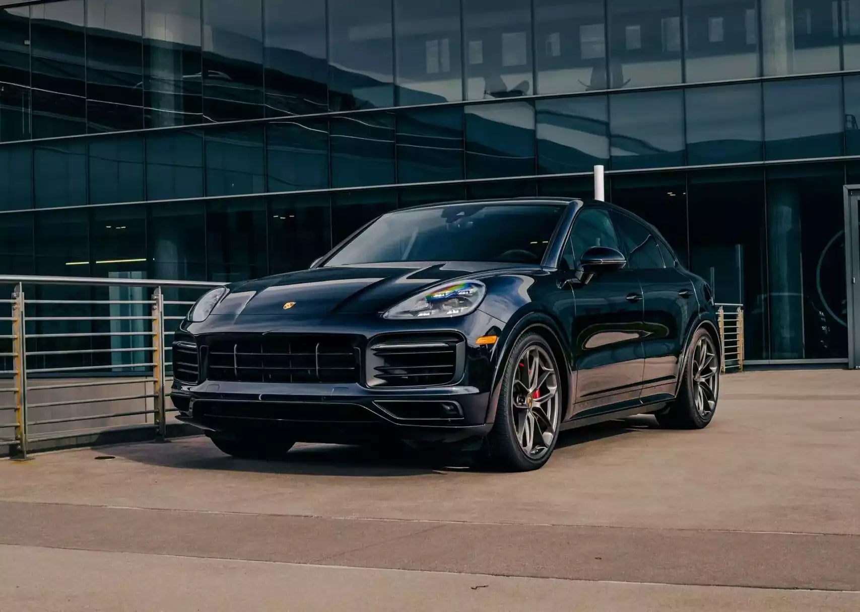 Black Porsche Cayenne SUV parked in front of a modern building