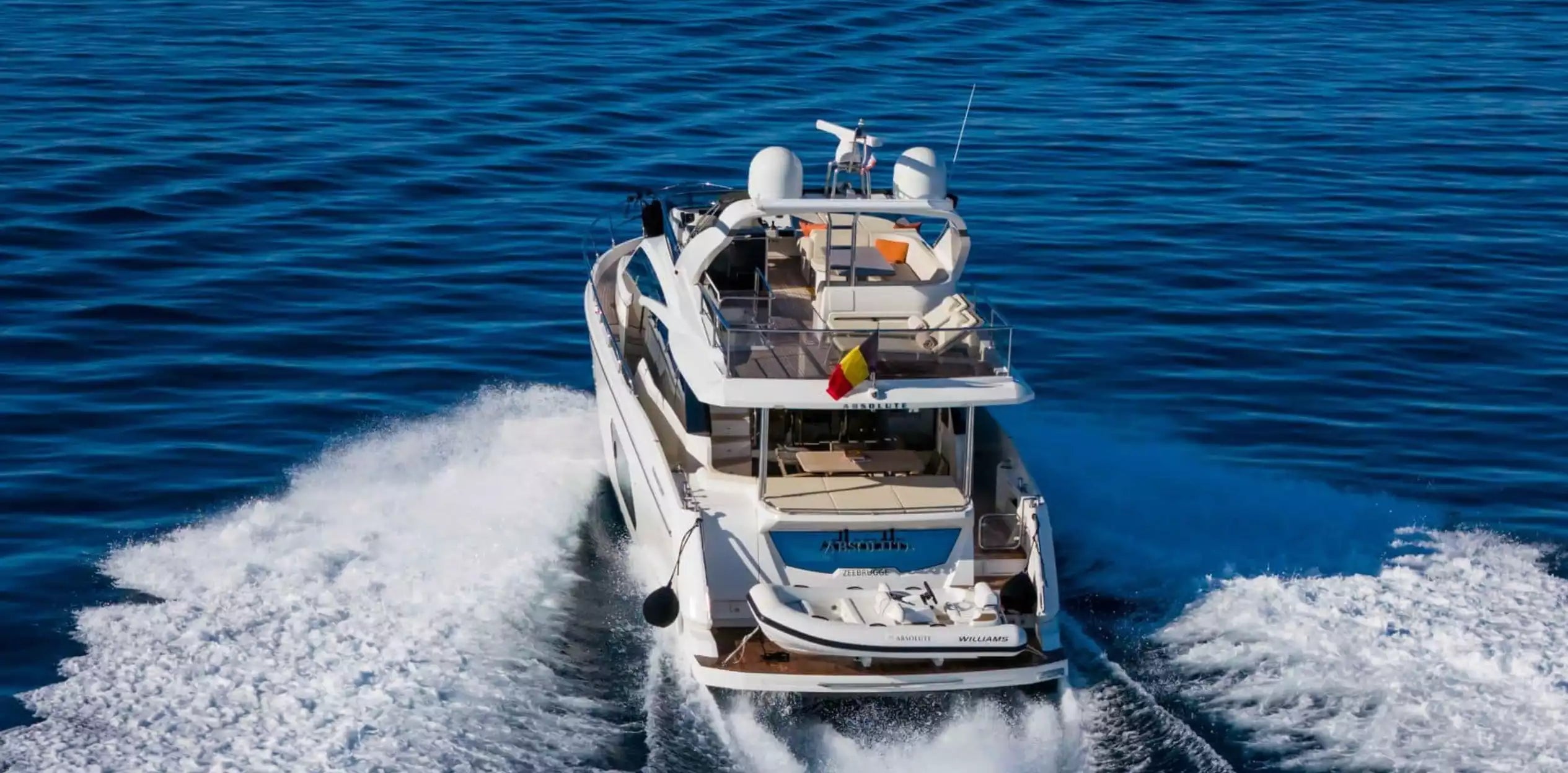 White boat speeding across a blue body of water