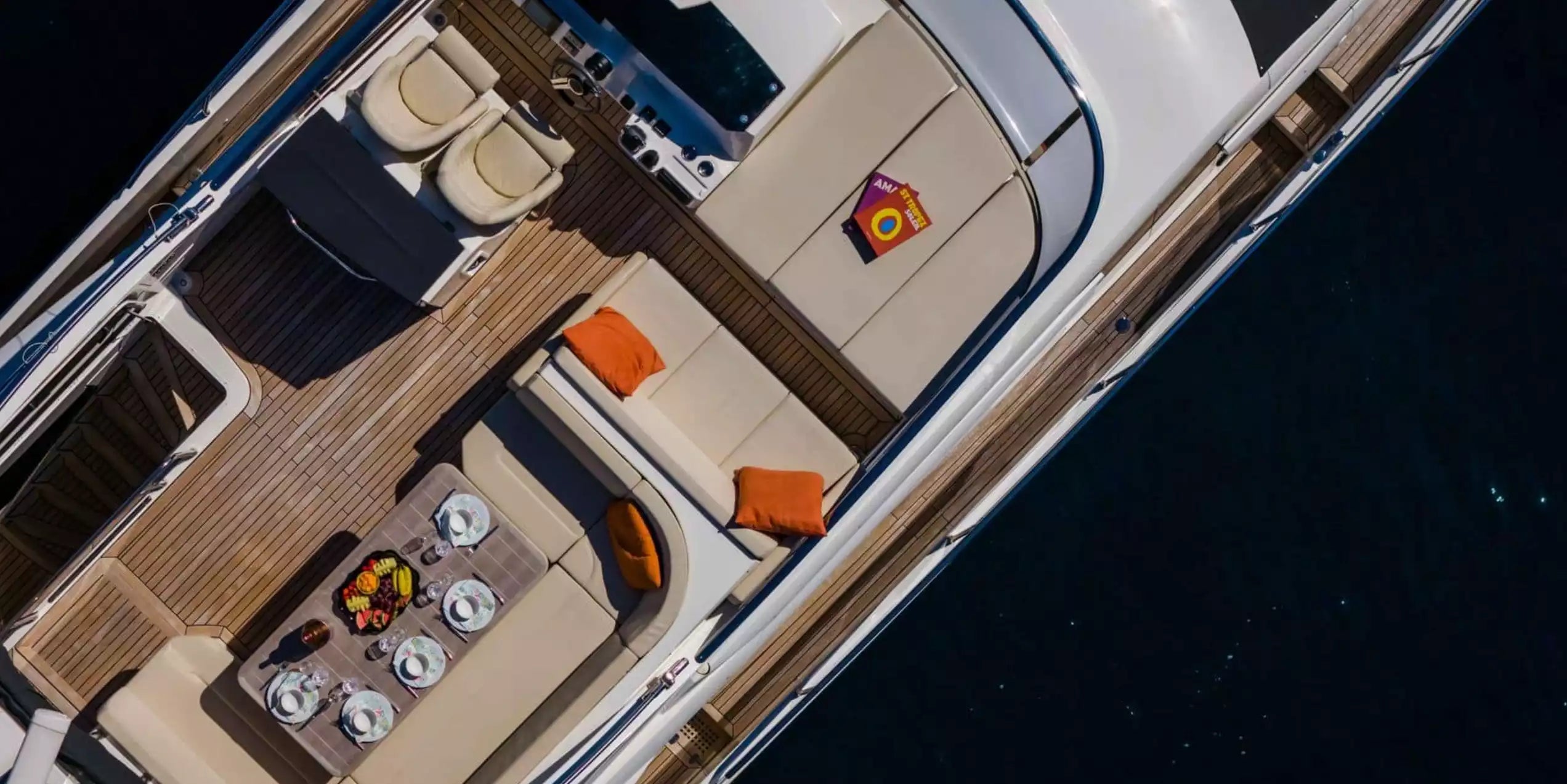 Top-down view of a boat's interior with beige seats and wooden floor.