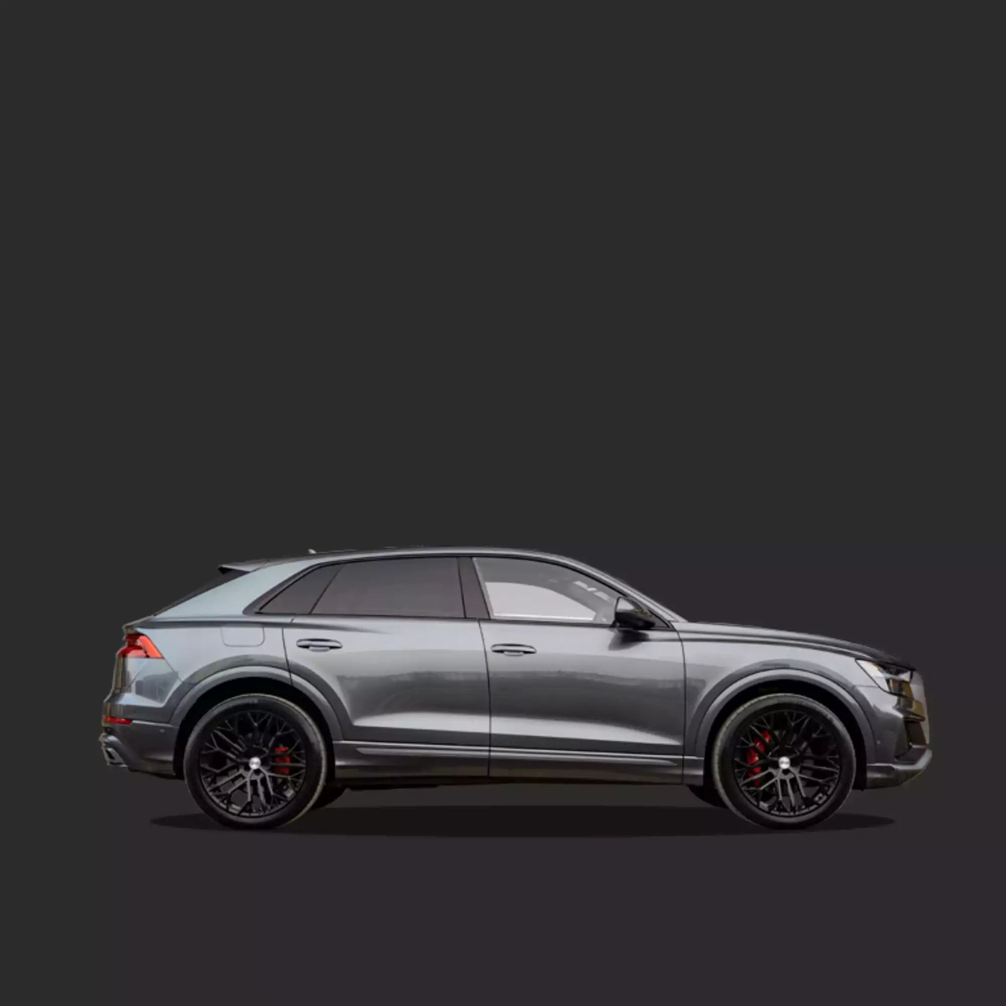 A side profile view of a metallic silver Audi Q8 SUV with black multi-spoke wheels and red brake calipers, set against a solid dark gray background.