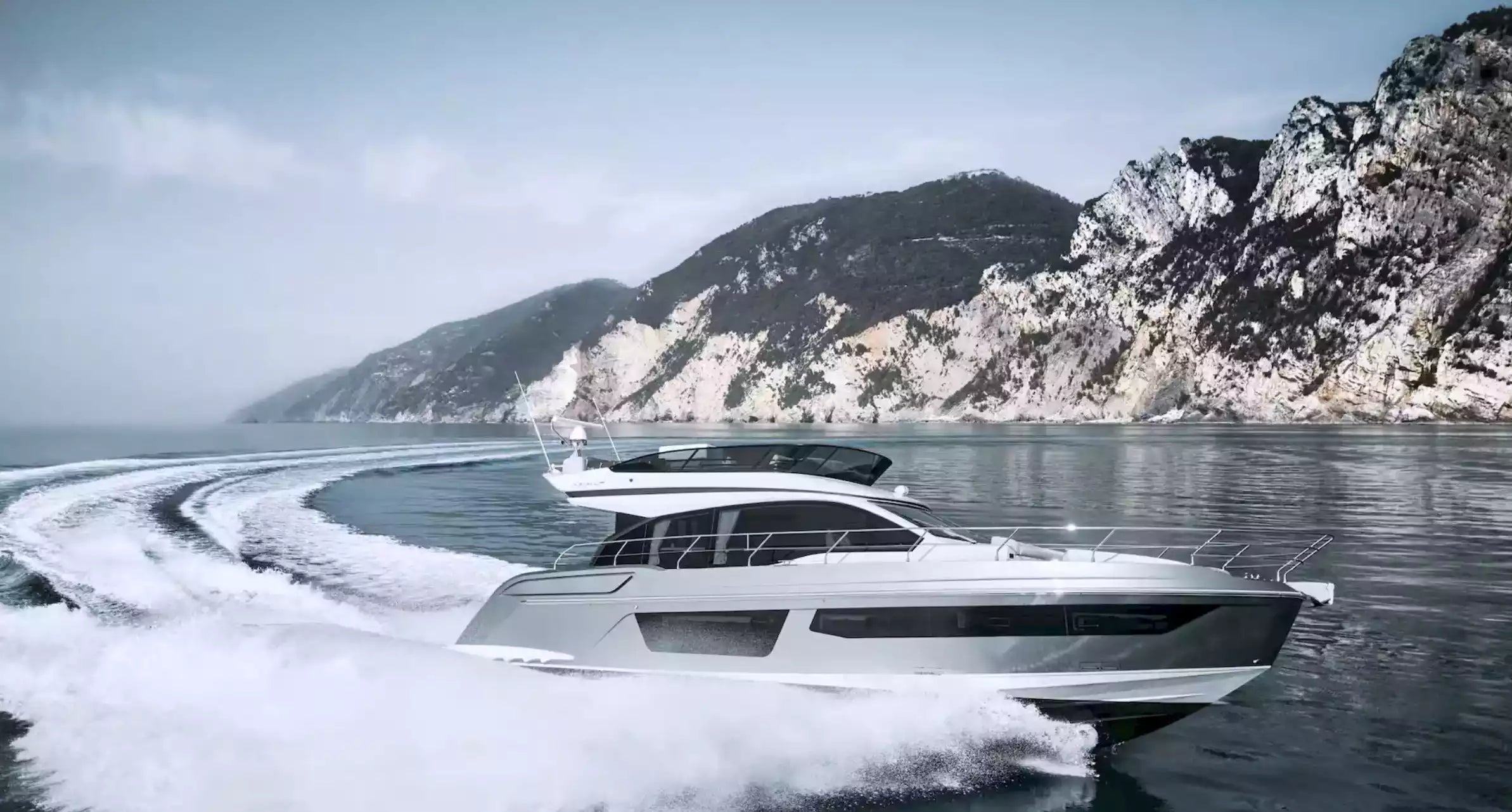 White yacht speeding on water with mountains in the background