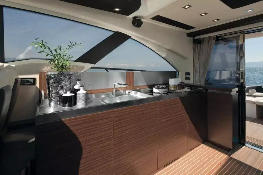 Modern yacht interior with kitchen area and large windows.