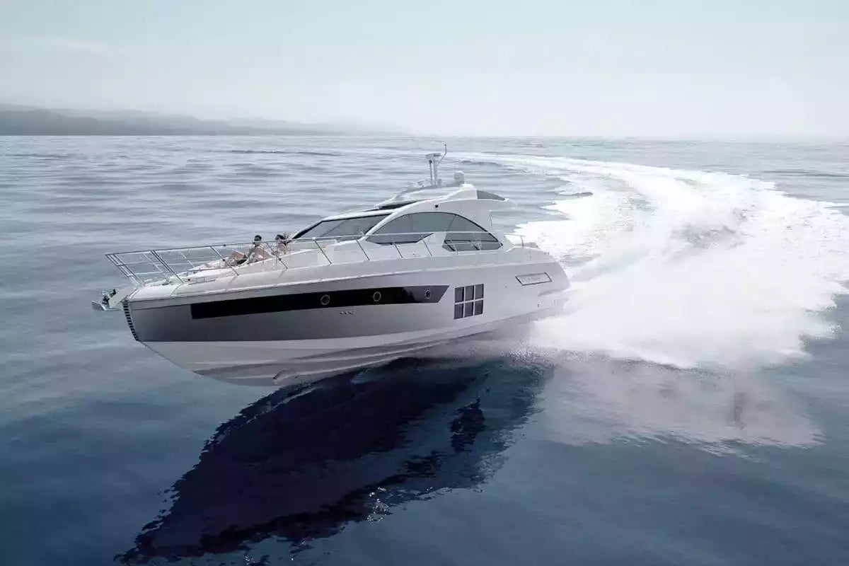 White yacht speeding across a calm blue sea with a clear sky.