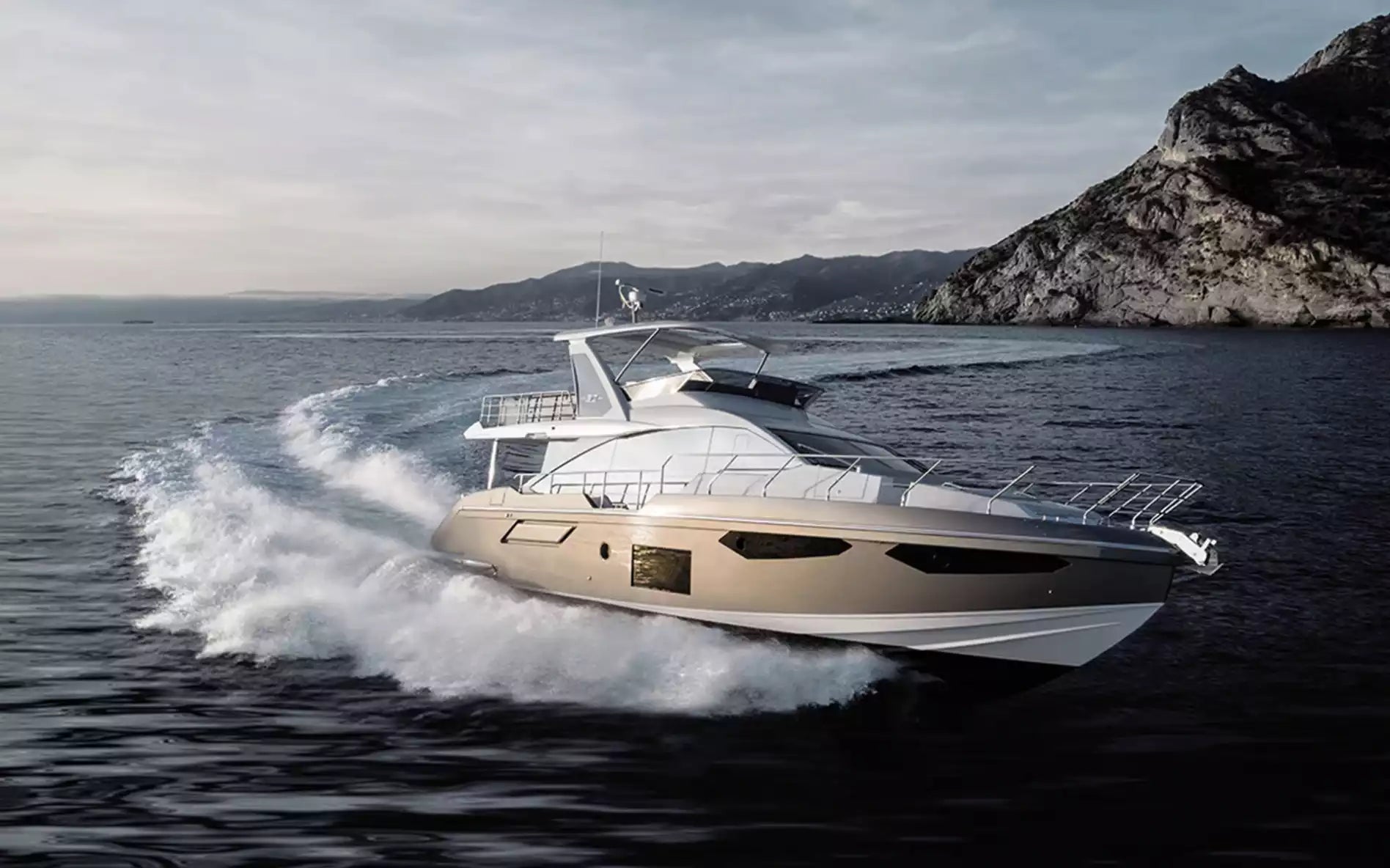 Yacht speeding on water with mountains in the background