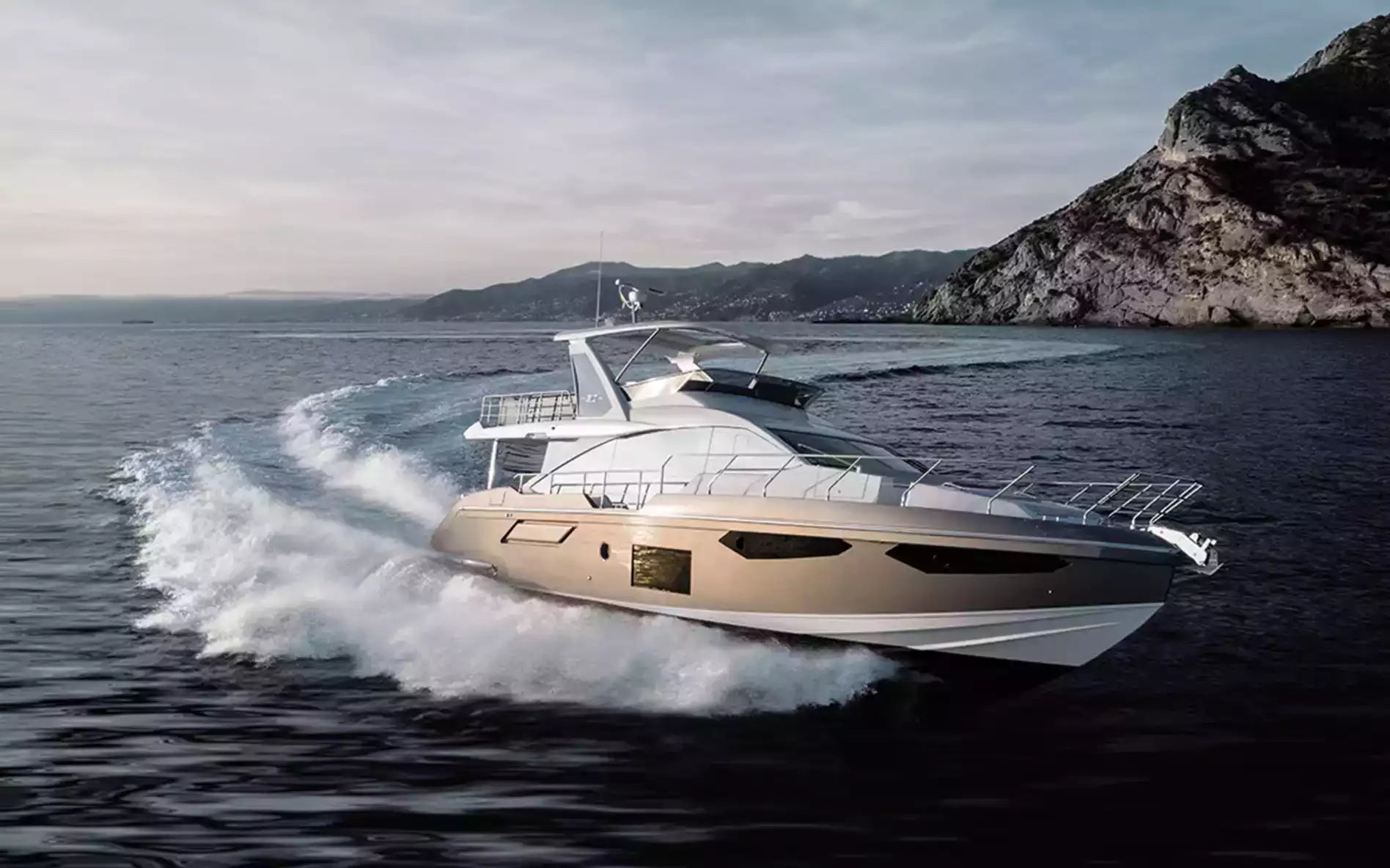 Yacht speeding on the water with a mountainous background