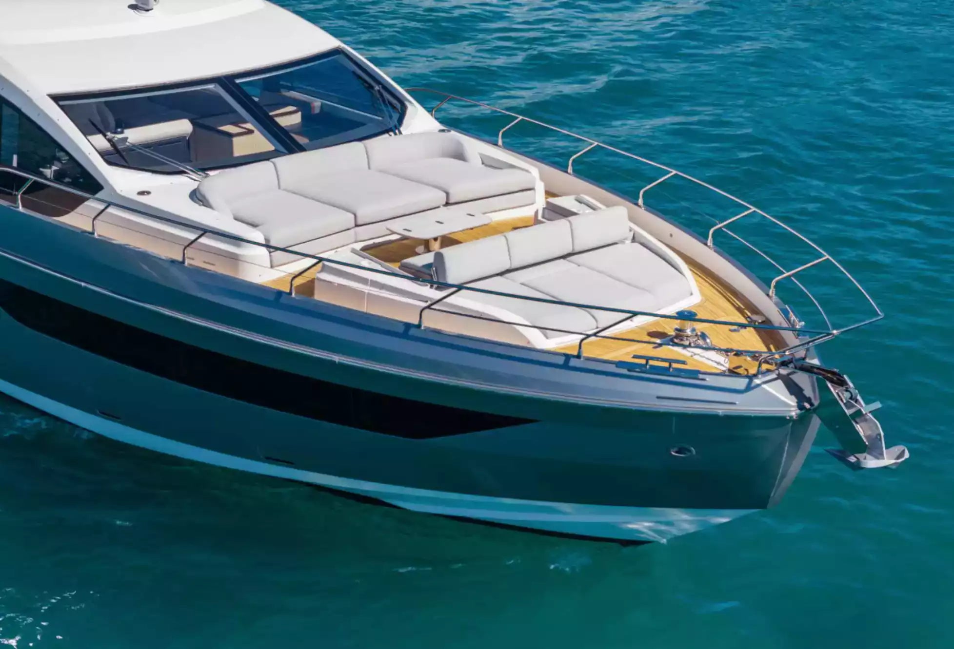 A luxury motor yacht with a white upper deck, gray hull, and yellow accents, shown sailing on clear turquoise water.