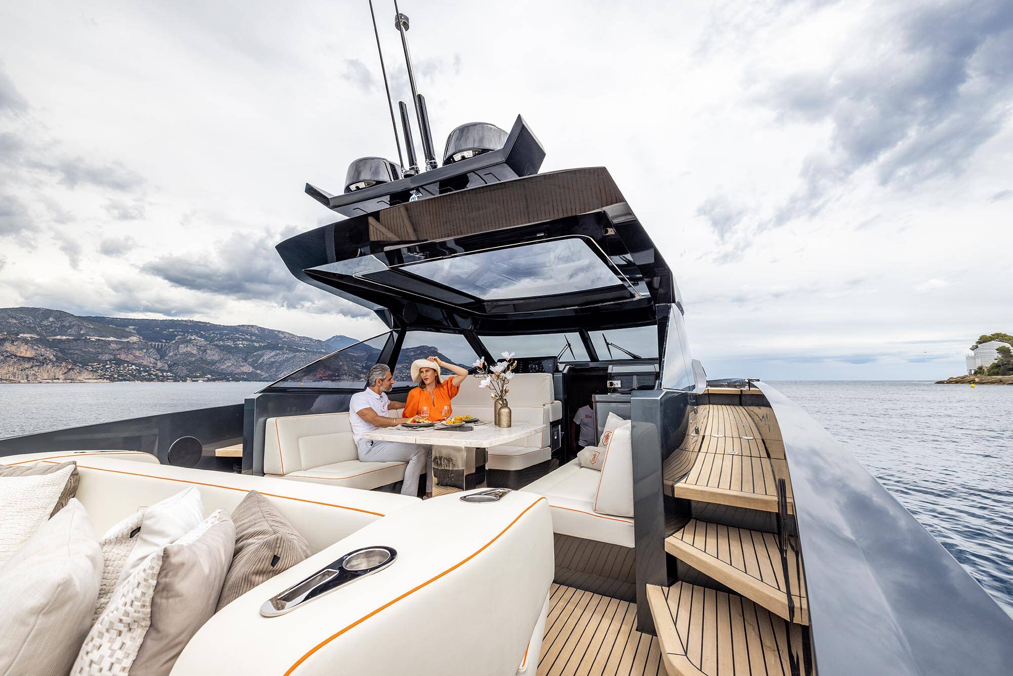 Luxury yacht on the water with a couple inside, surrounded by scenic landscape.