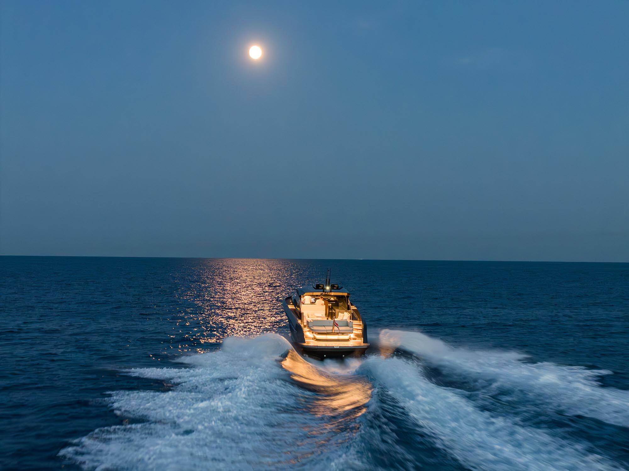 Boat on the water at night with a full moon in the sky