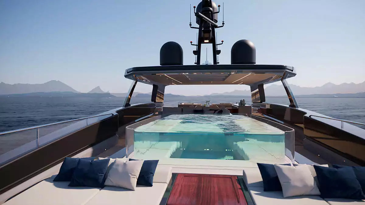 A luxury yacht deck featuring a rectangular infinity pool, outdoor lounge seating with navy and white pillows, and an open upper deck with radar domes and a mast against a blue ocean and mountain backdrop.