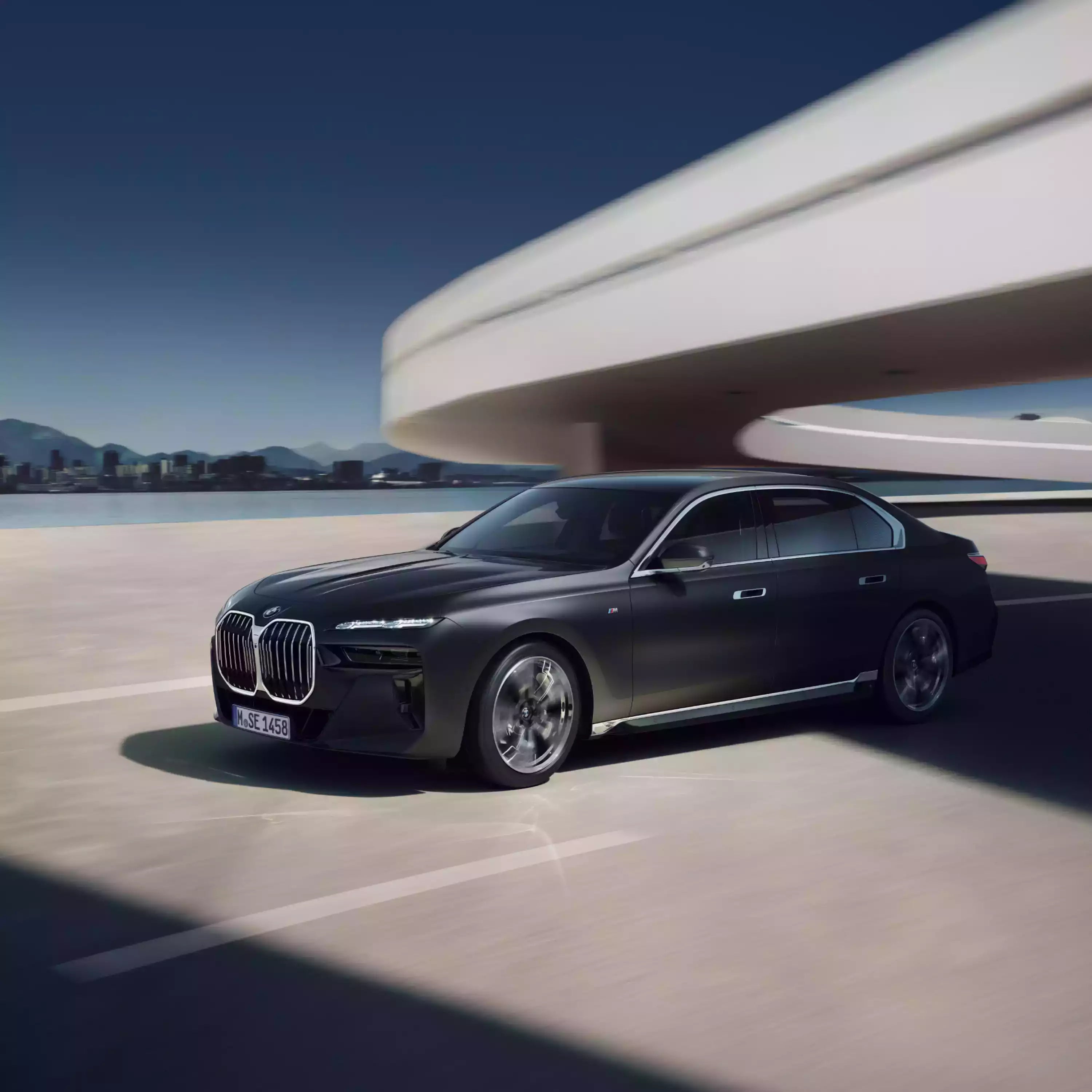 Black BMW car parked in front of a modern architectural structure with a clear blue sky.