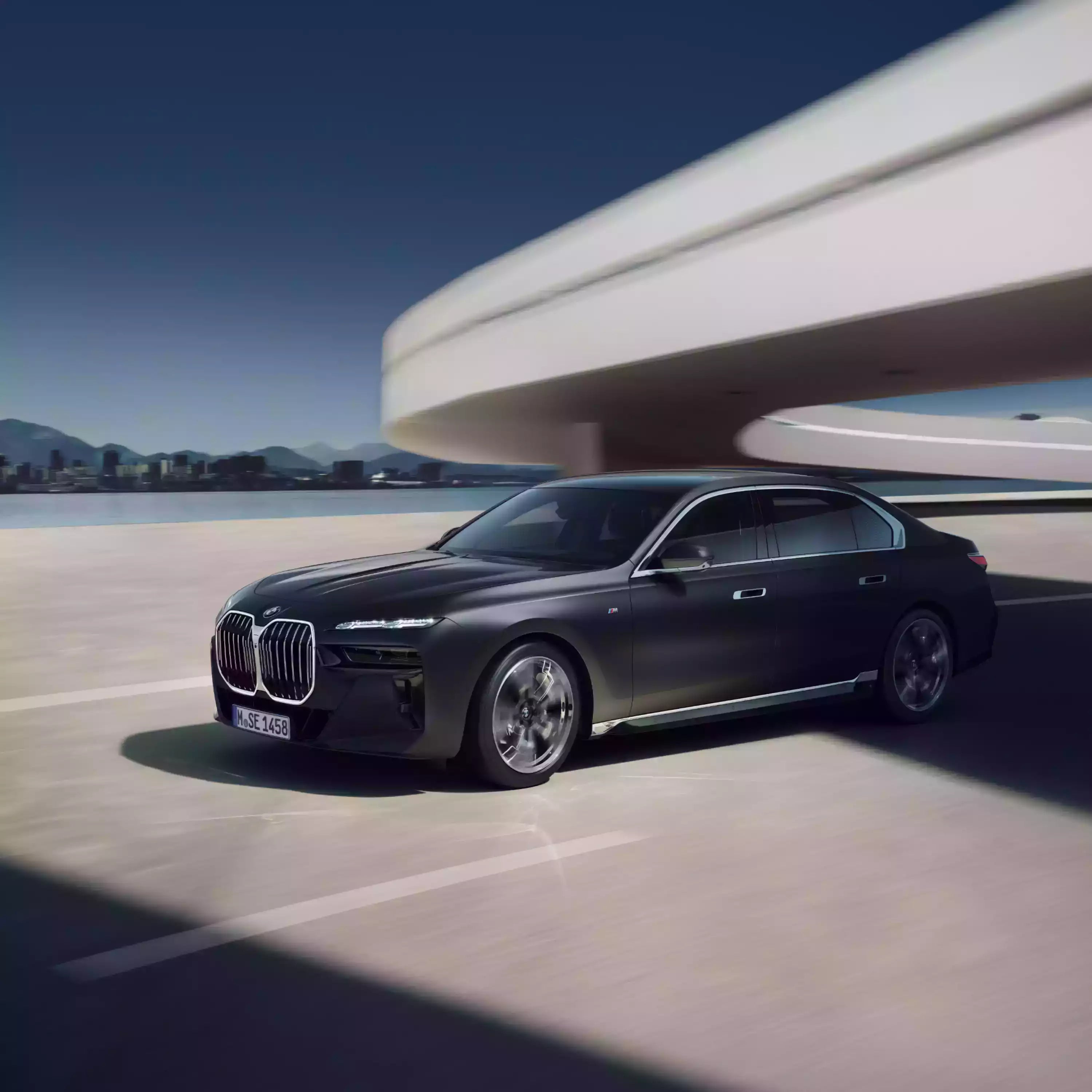 Black BMW car on a road with modern architecture and blue sky in the background