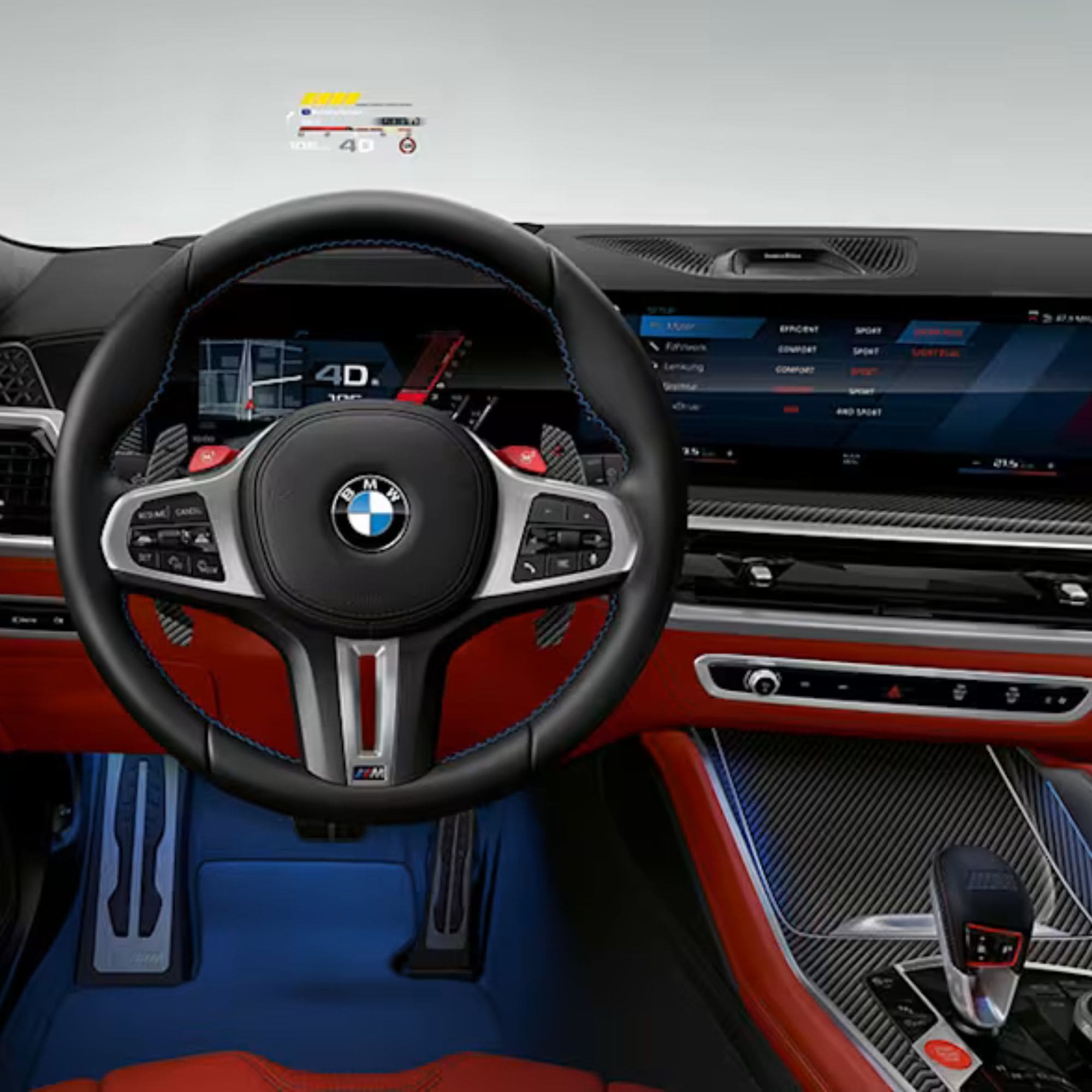 A close-up view of a luxury car interior featuring a black leather steering wheel with blue stitching, a silver BMW logo, a digital instrument cluster, a large infotainment screen, red leather trim, and blue seats.