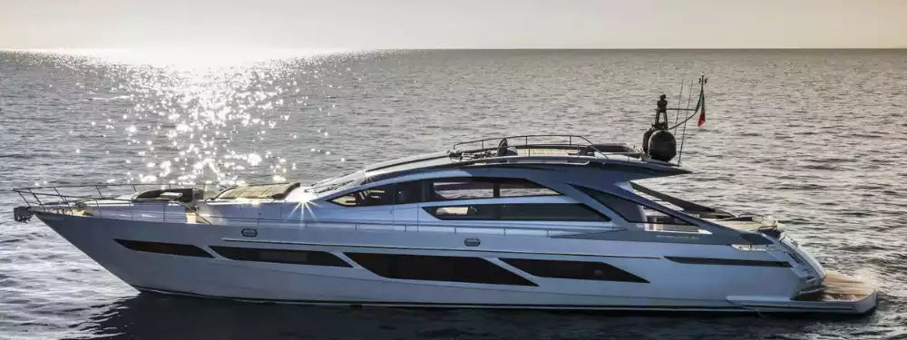 A luxury motor yacht with a white hull and dark gray superstructure, sailing on calm blue water under bright sunlight with sparkling reflections.