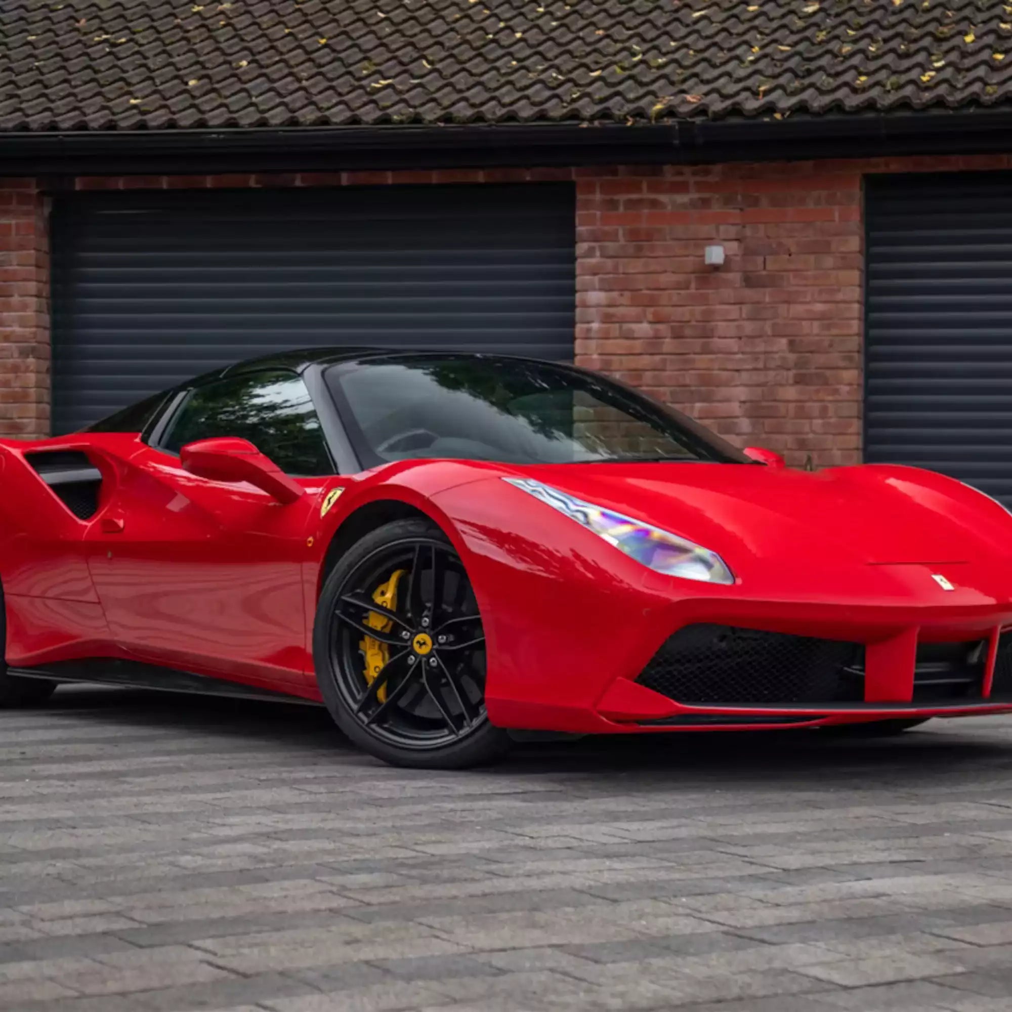 Red sports car parked in front of a brick building