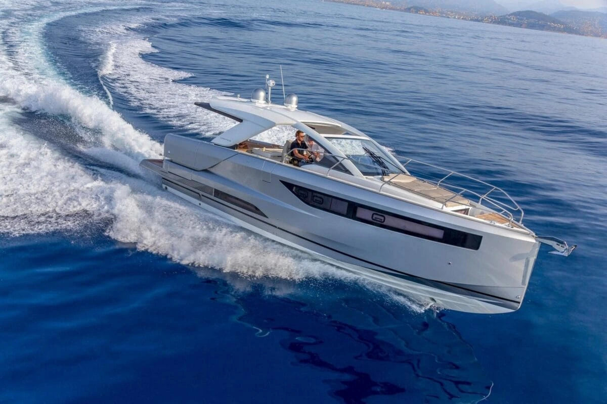 White speedboat cutting through blue water with a clear sky