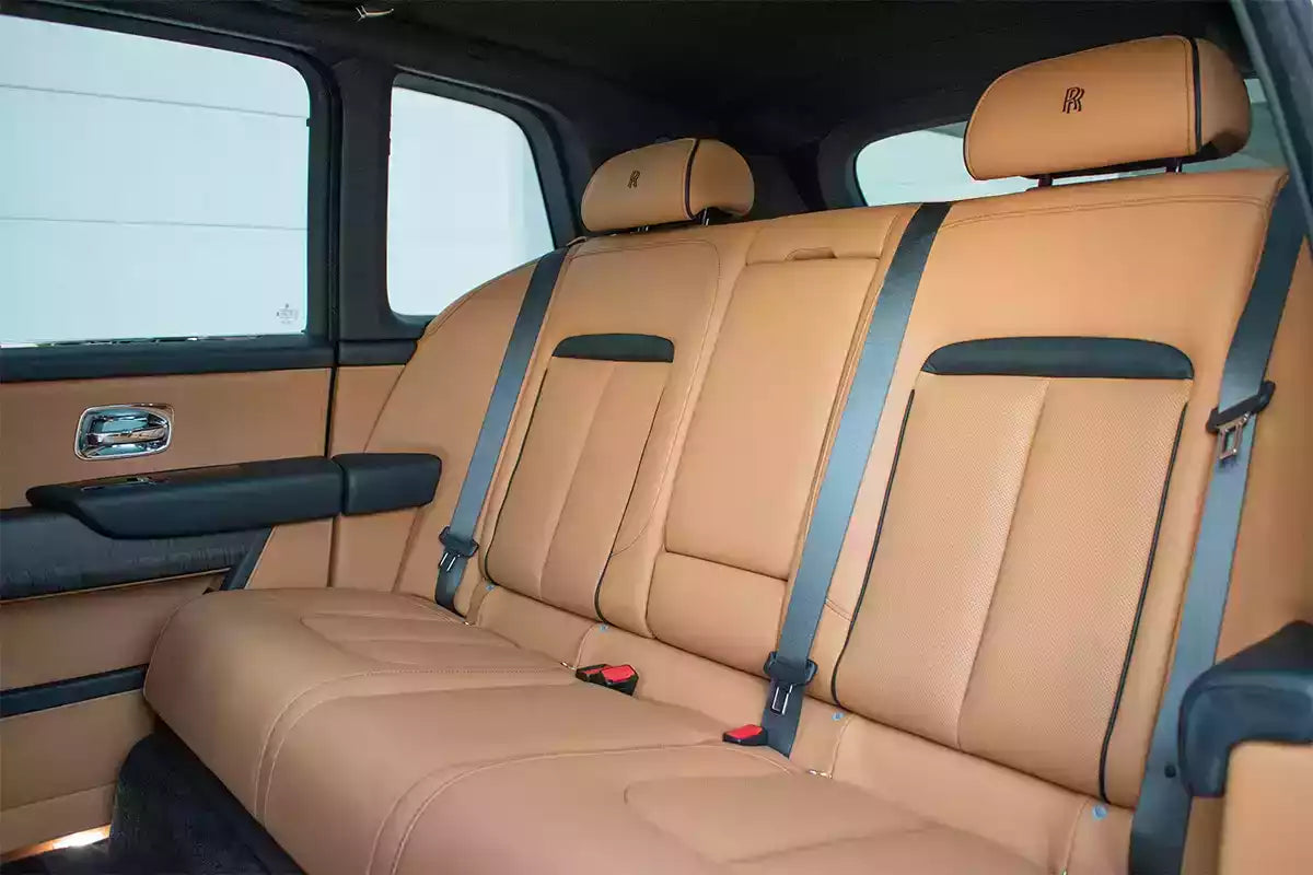Beige car interior with headrests and seat belts in a vehicle.