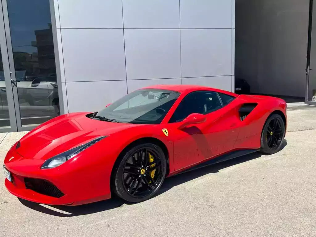 Red Ferrari sports car parked in front of a modern building.