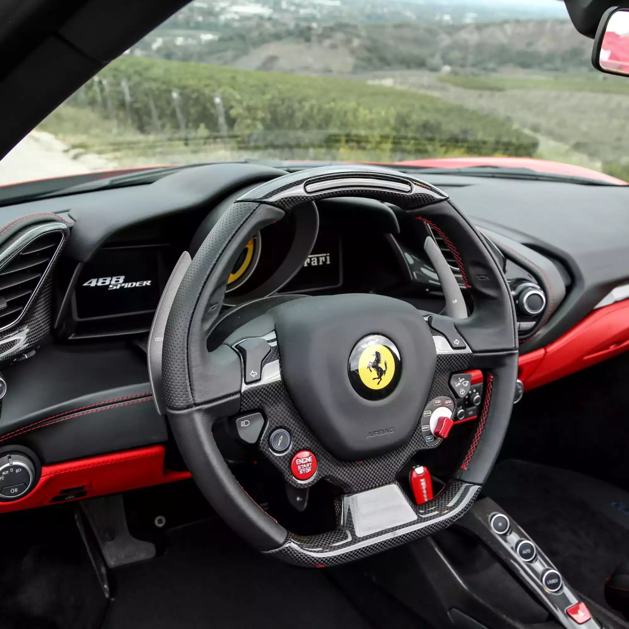 Steering wheel of a Ferrari car with a scenic background