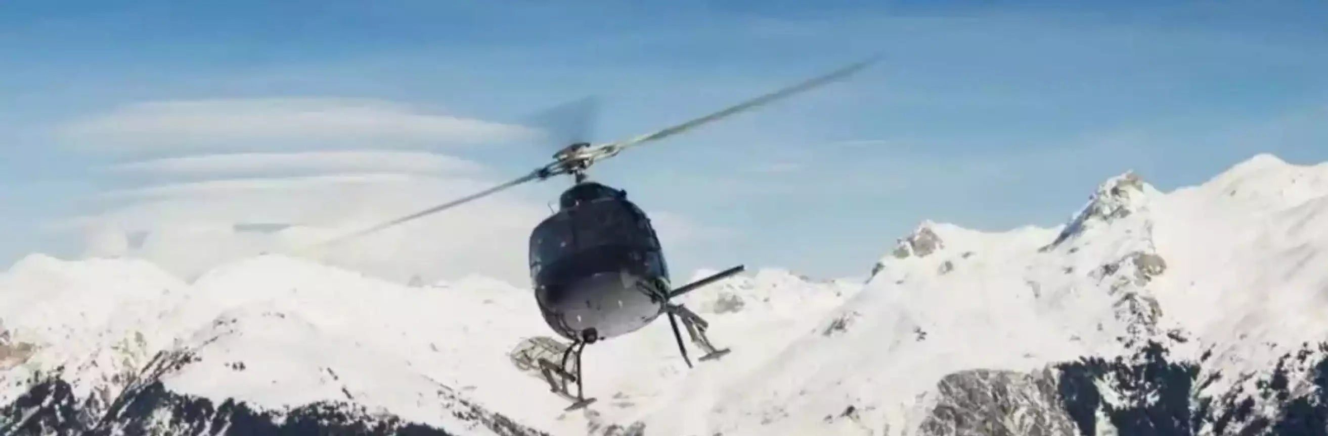 Helicopter flying over a snowy mountain landscape