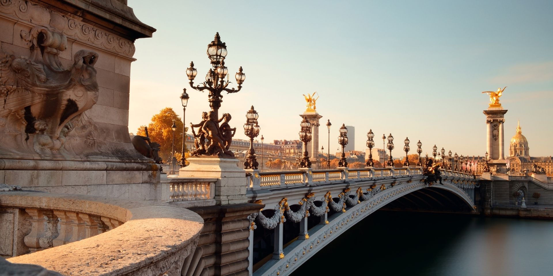 Elegant bridge with architectural details and street lamps at sunset.