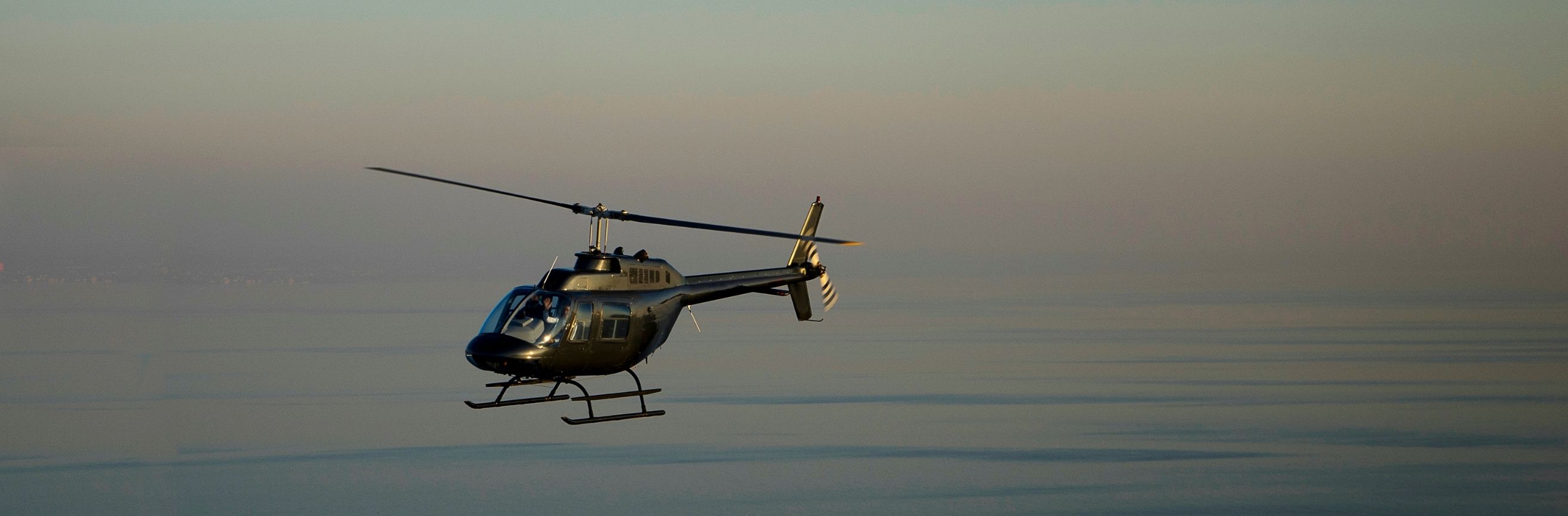 Helicopter flying against a clear sky during sunset or sunrise.