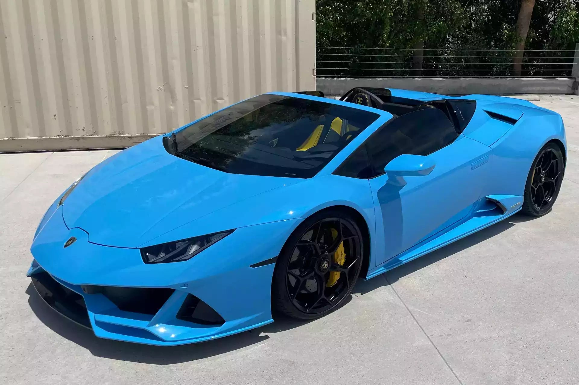 Blue sports car parked on a concrete surface with a building in the background