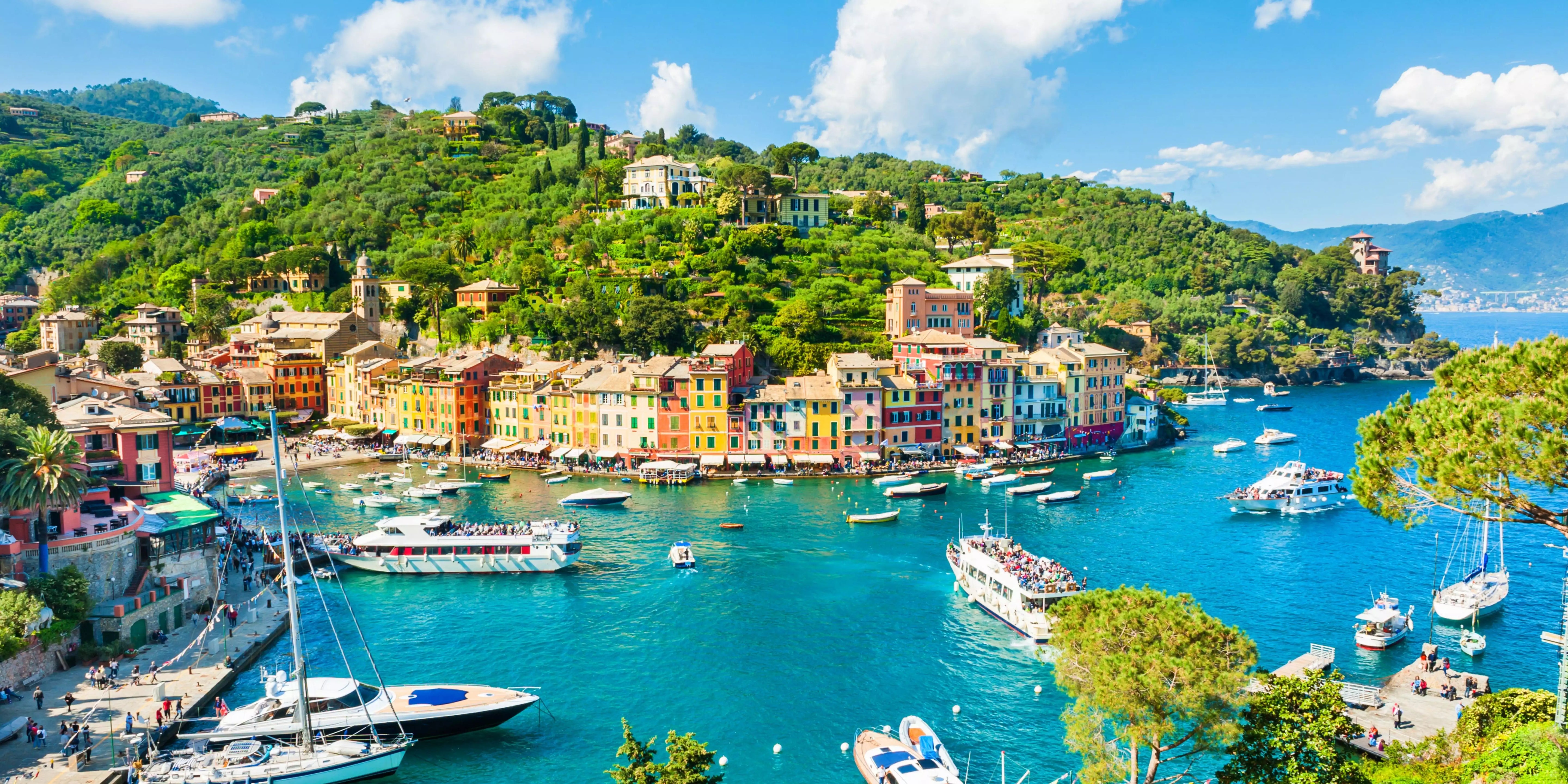 Colorful coastal town with boats in a bay under a blue sky.