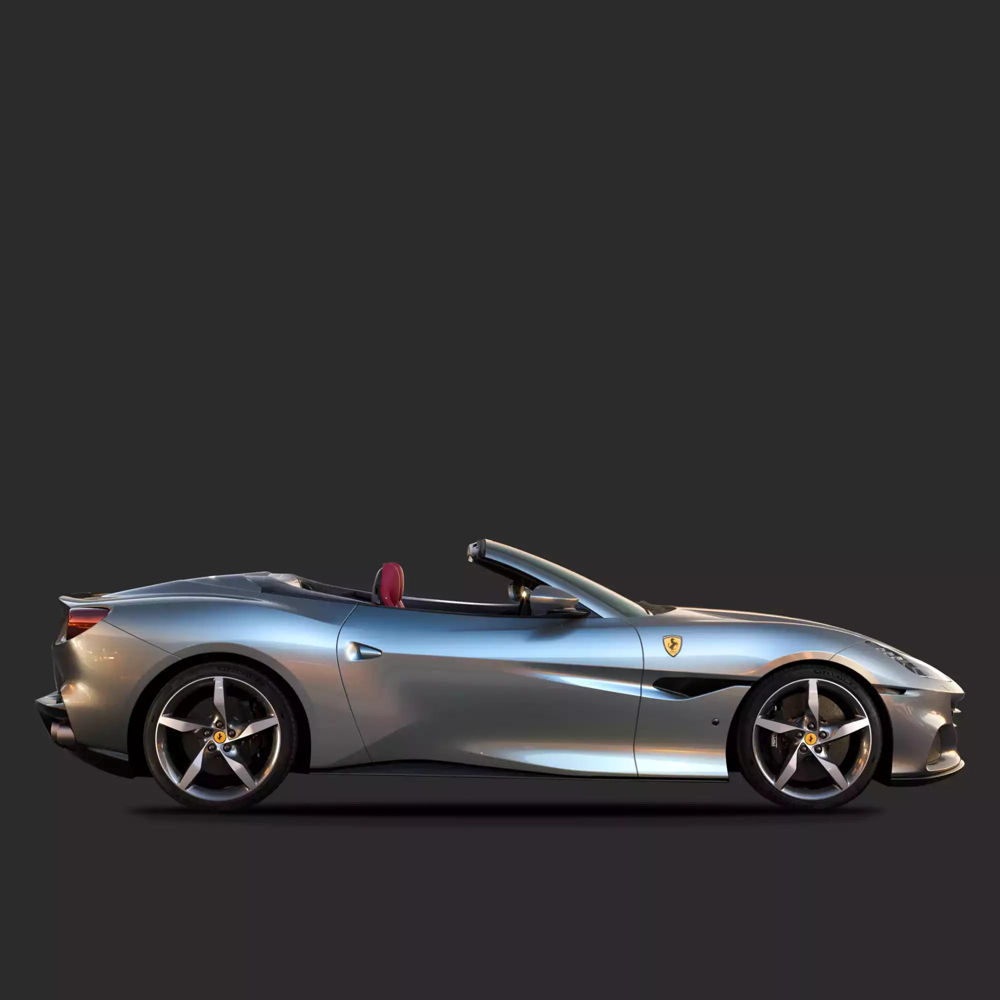 A silver Ferrari Portofino convertible sports car shown in a side profile view against a dark gray studio background.