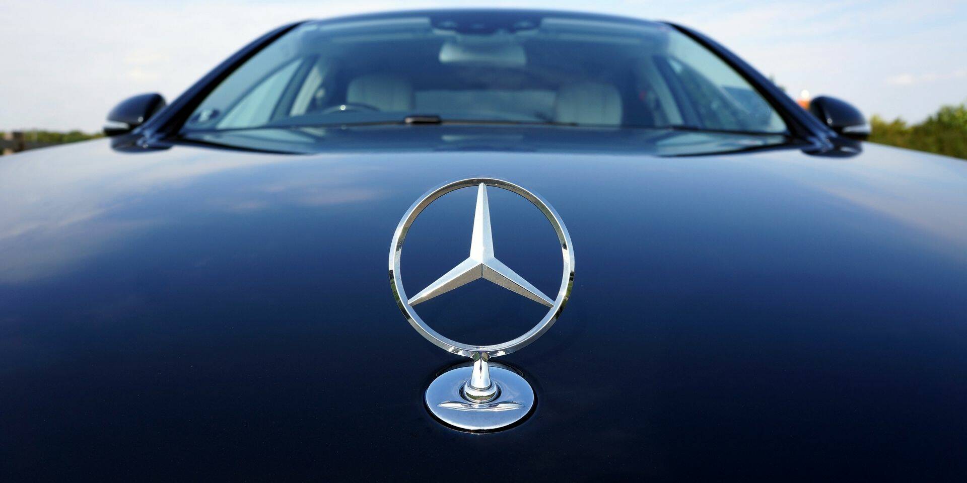 Mercedes-Benz logo on a black car with a blurred natural background