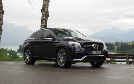 Black Mercedes-Benz SUV parked on a road with a scenic background