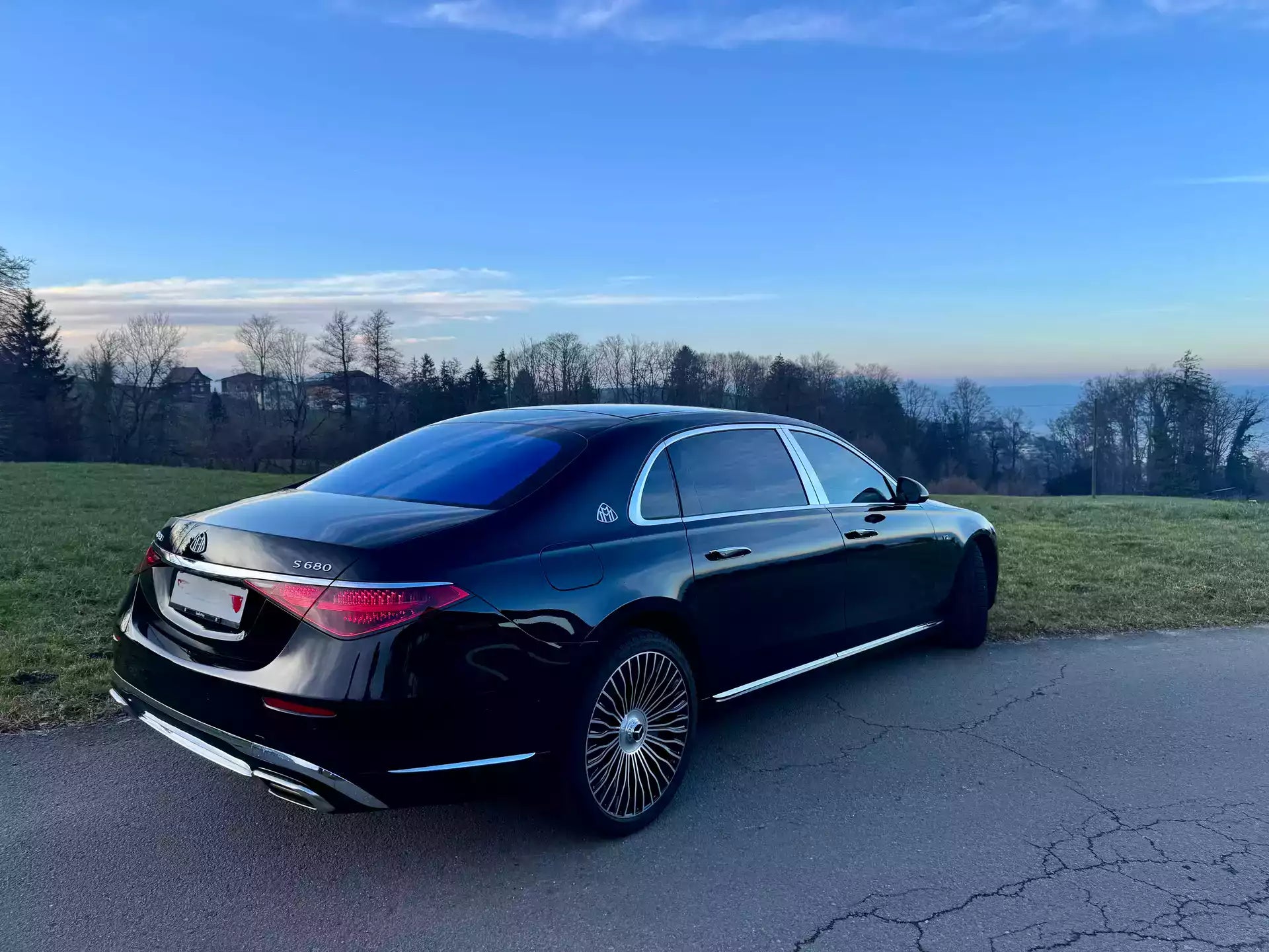 Black luxury car parked on a road with a scenic background
