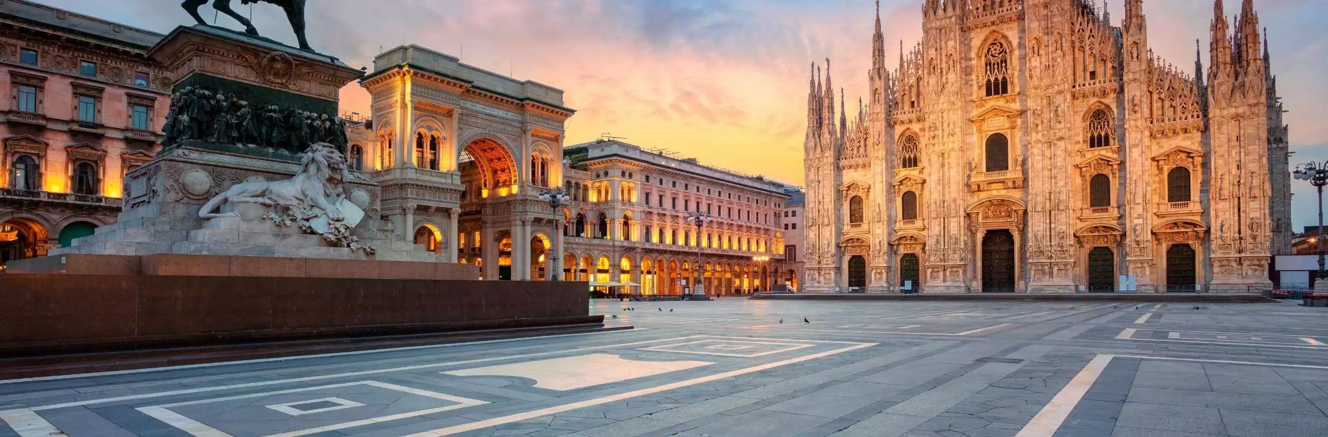 Sunset view of a large cathedral and surrounding buildings in an urban square.