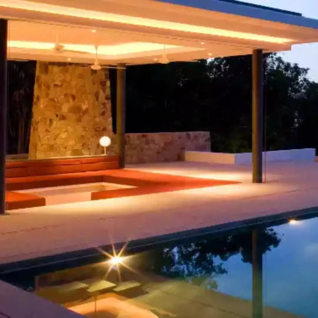 Modern villa with a pool and surrounding greenery under a clear blue sky.